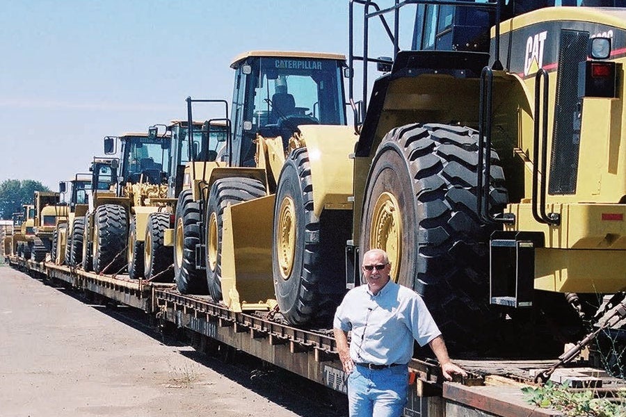 Peterson sales manager Allan Emmons posing with a long line of Cat wheel loaders and excavators